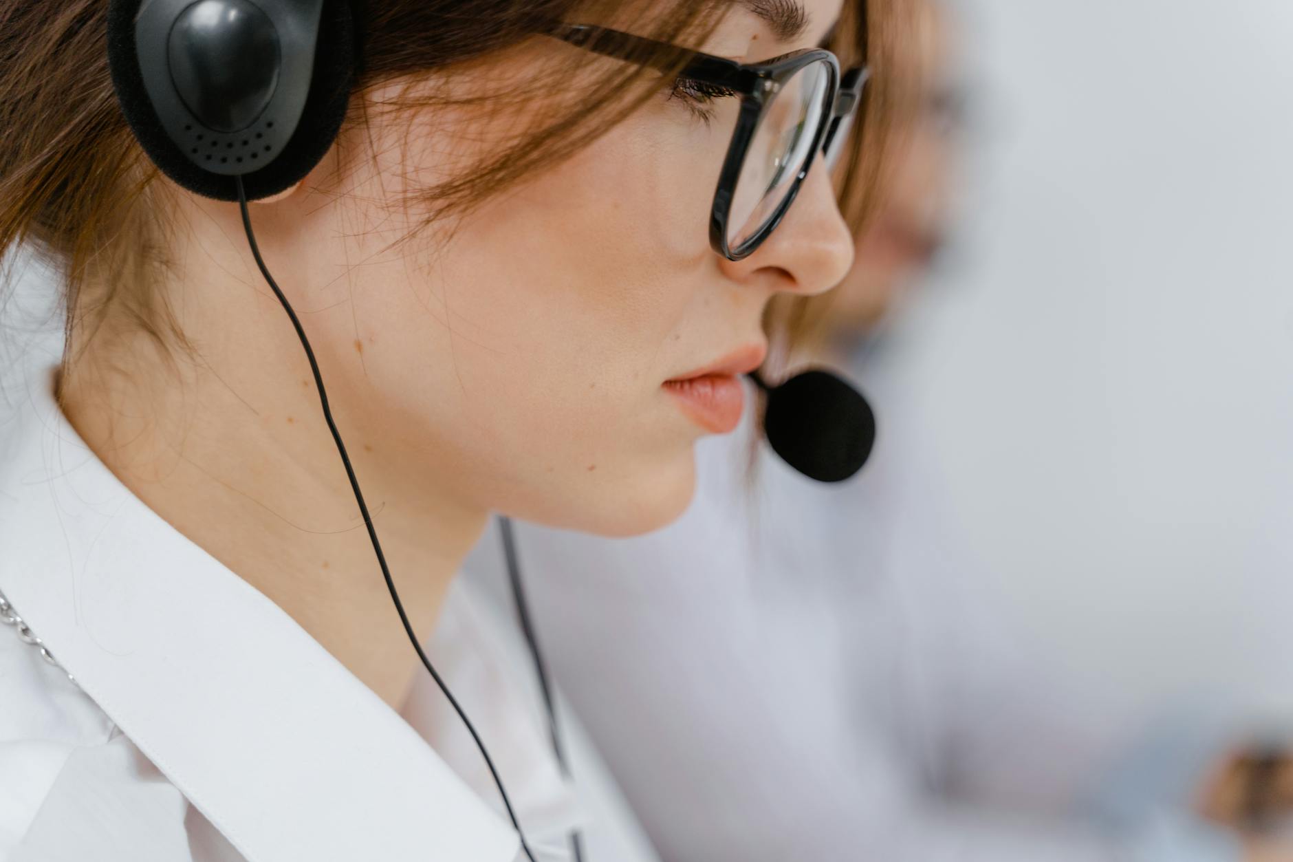 woman wearing eyeglasses with black headset and mouthpiece