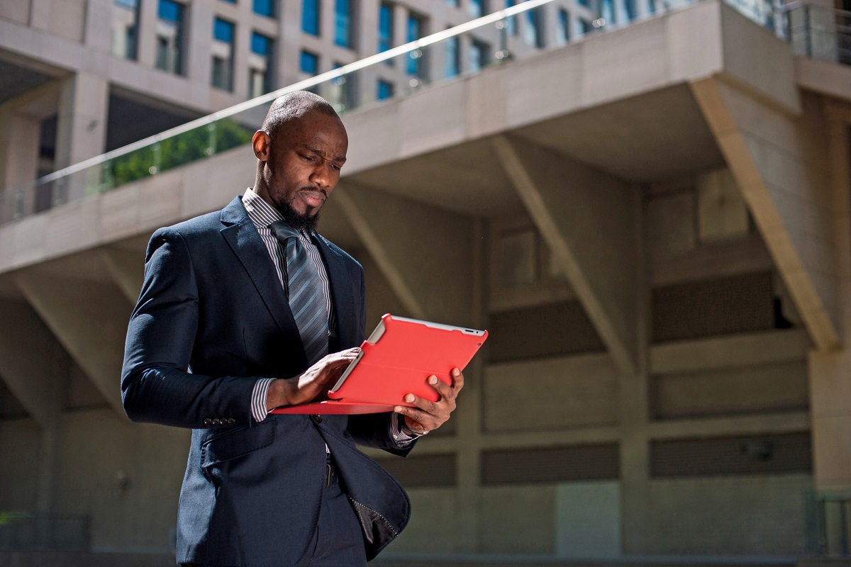 Black businessman looking at his tablet computer in urban backgr